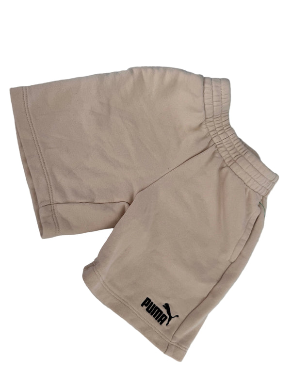Beige Puma athletic shorts with an elastic waistband and a black Puma logo on the left leg, laid flat on a light gray background.