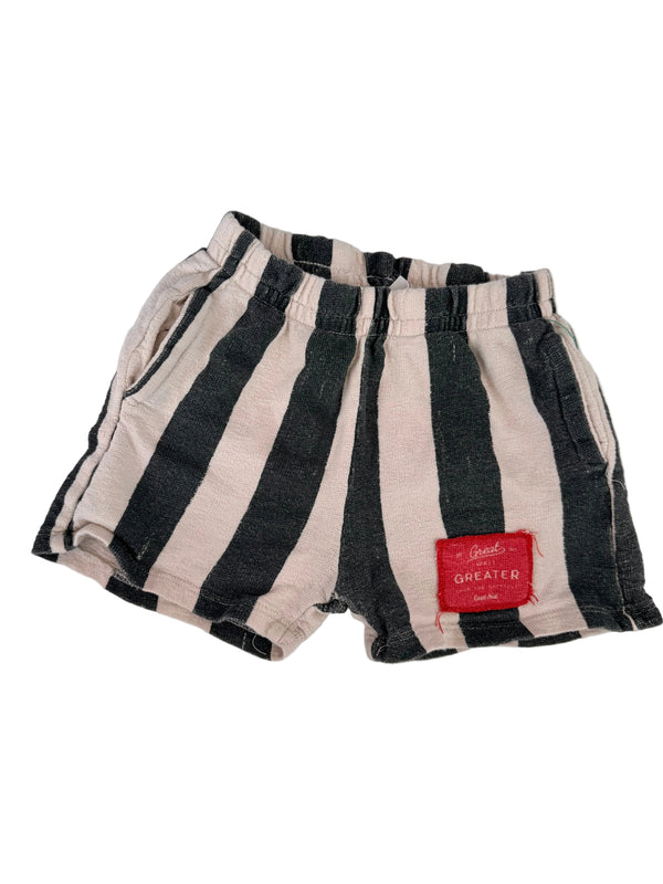 A pair of striped shorts with alternating black and off-white horizontal stripes, featuring a red fabric brand label on the side. The shorts are laid flat on a white background.