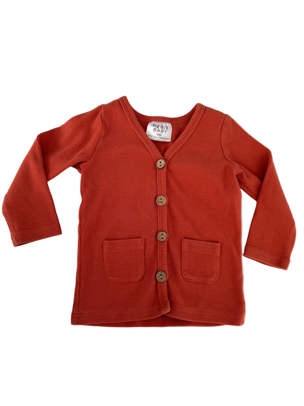 A rust-orange ribbed knit cardigan sweater with long sleeves, button closure, and front pockets, laid flat on a white background.