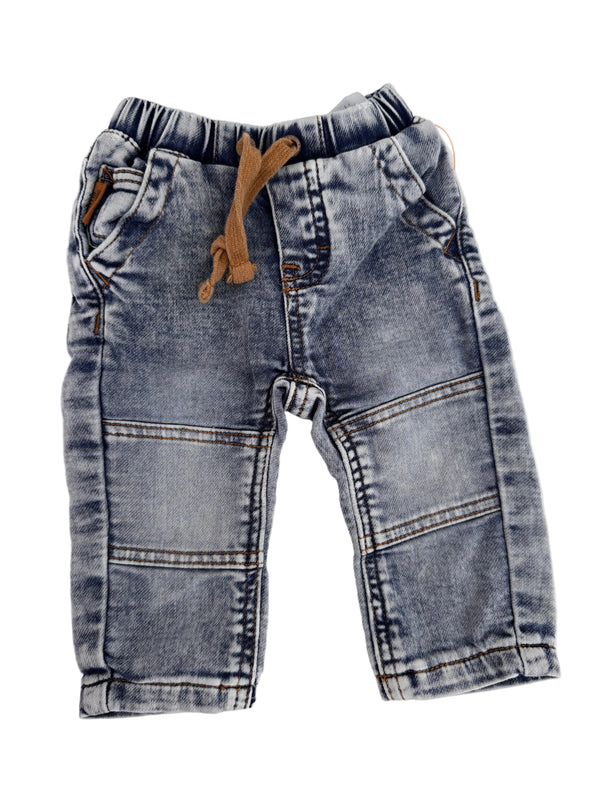 A pair of faded light blue denim jeans for toddlers, laid flat on a white background. The jeans feature a light wash with darker blue shading, classic front patch pockets, and a brown fabric drawstring at the elastic waistband.