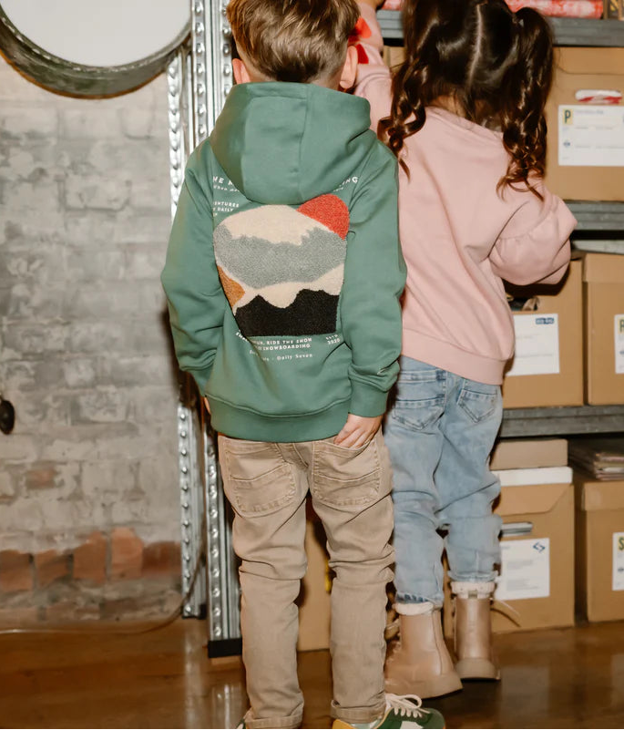 Two children standing in a storage area with boxes and shelves.