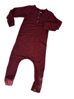 Load image into Gallery viewer, A burgundy long-sleeve one-piece jumpsuit with a three-button henley neckline, laid flat on a white surface with dappled shadows.

