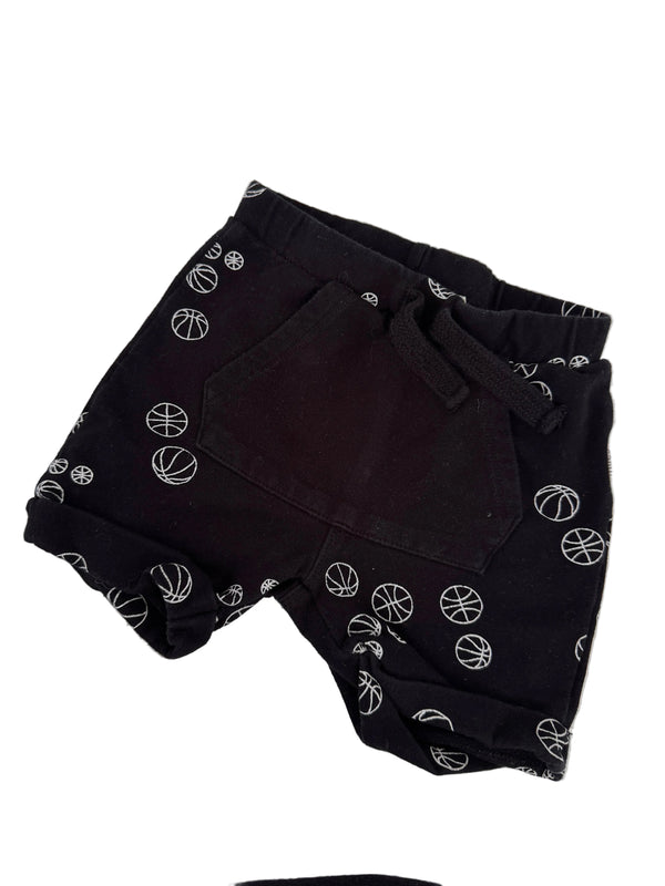 Black shorts with a white basketball print pattern, laid flat on a white surface.