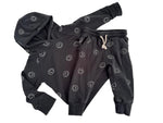 Load image into Gallery viewer, A children's dark gray hooded sweatshirt and matching jogger pants set, both featuring an all-over white smiley face pattern. The hoodie has a hood and long sleeves, while the joggers have an elastic waistband with a white drawstring.
