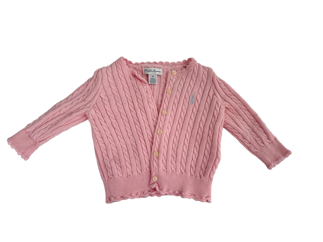A pink cable-knit cardigan sweater for toddlers, featuring a button-up front, three-quarter sleeves, and a small embroidered polo player logo on the chest, laid flat on a light gray fabric background.
