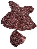 Load image into Gallery viewer, A matching two-piece clothing set consisting of a short-sleeve puff-sleeve top and a coordinating bonnet, both featuring a dense small floral print in dark reddish-brown, pink, and white, laid flat on a white surface with dappled shadows.
